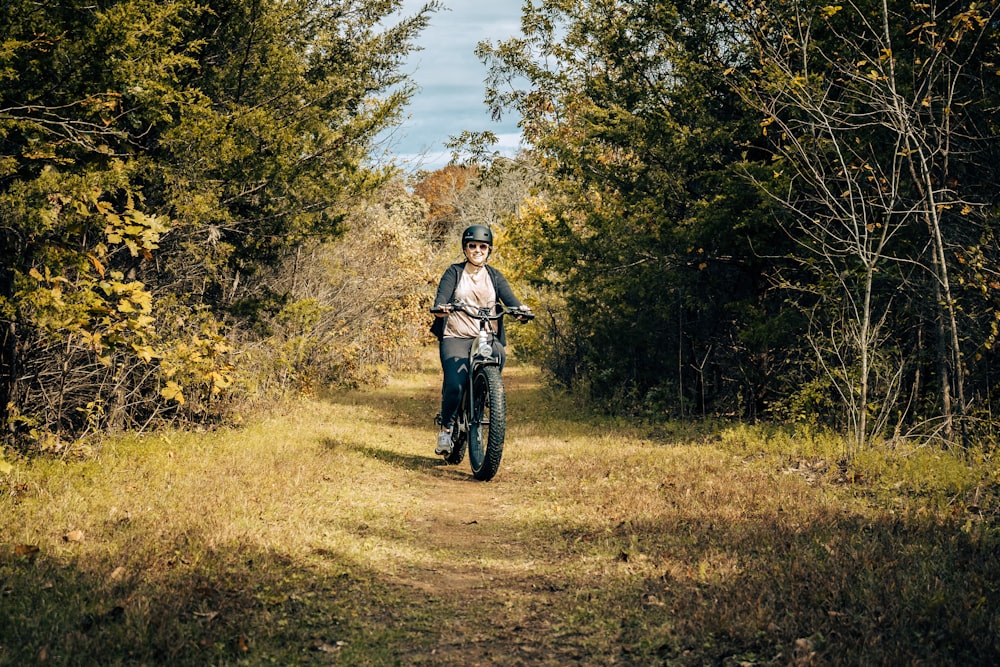 a woman riding a bike down a dirt road