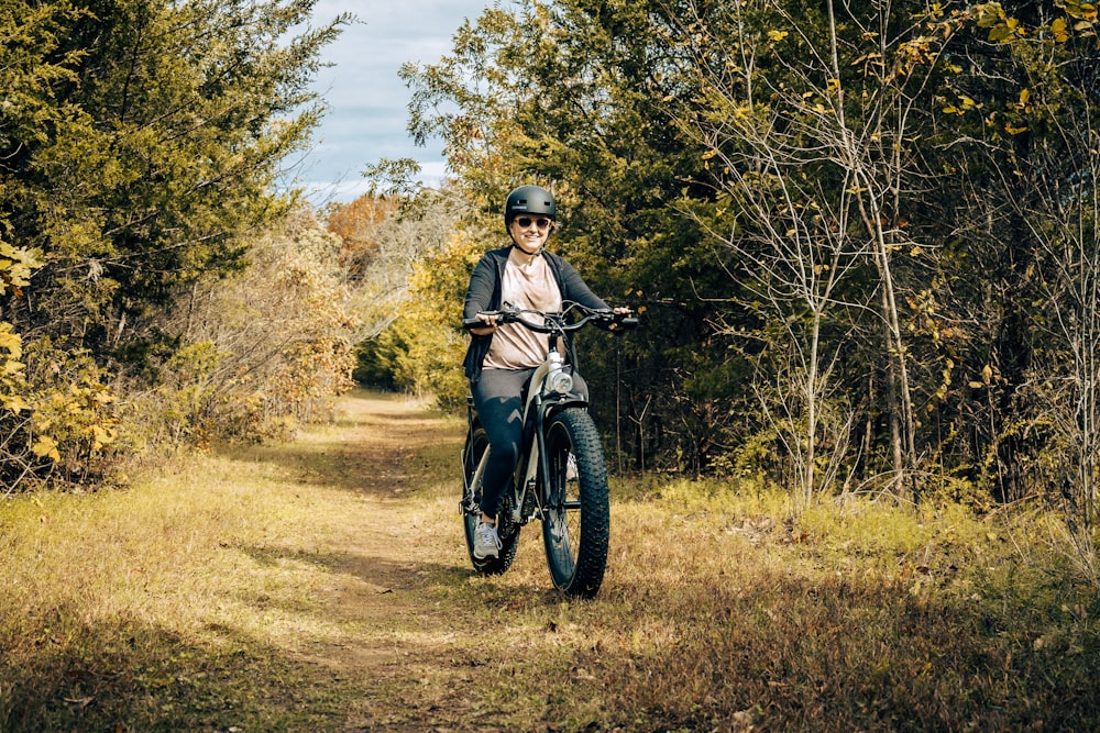 a woman riding a bike down a dirt road