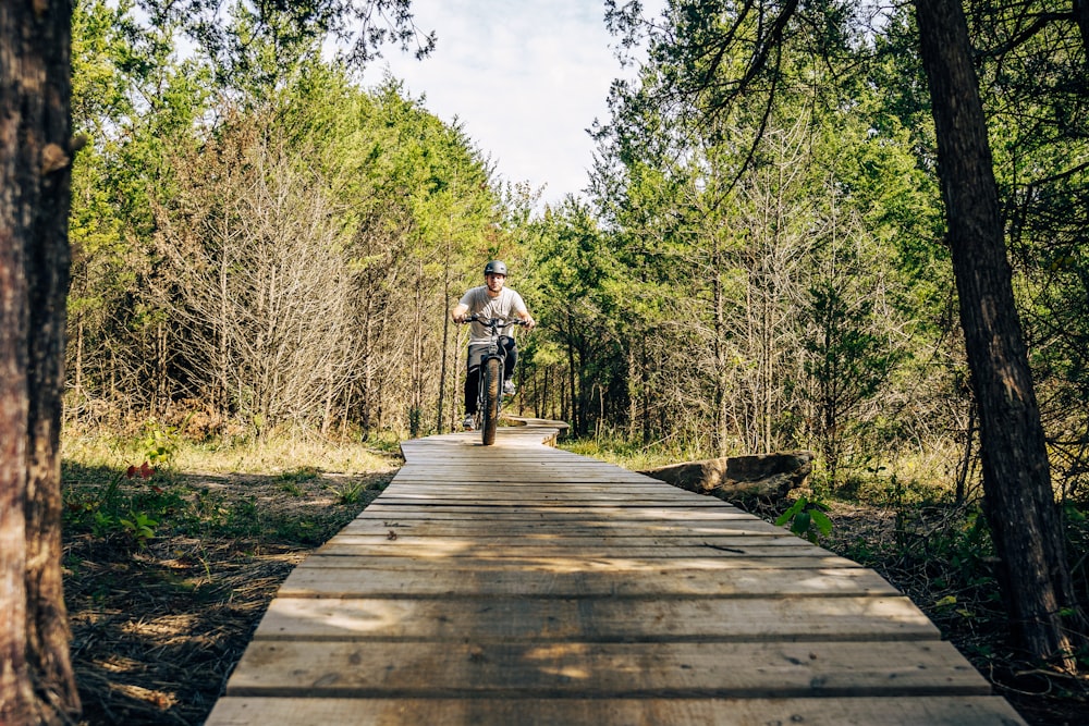 a man riding a bike down a wooden walkway