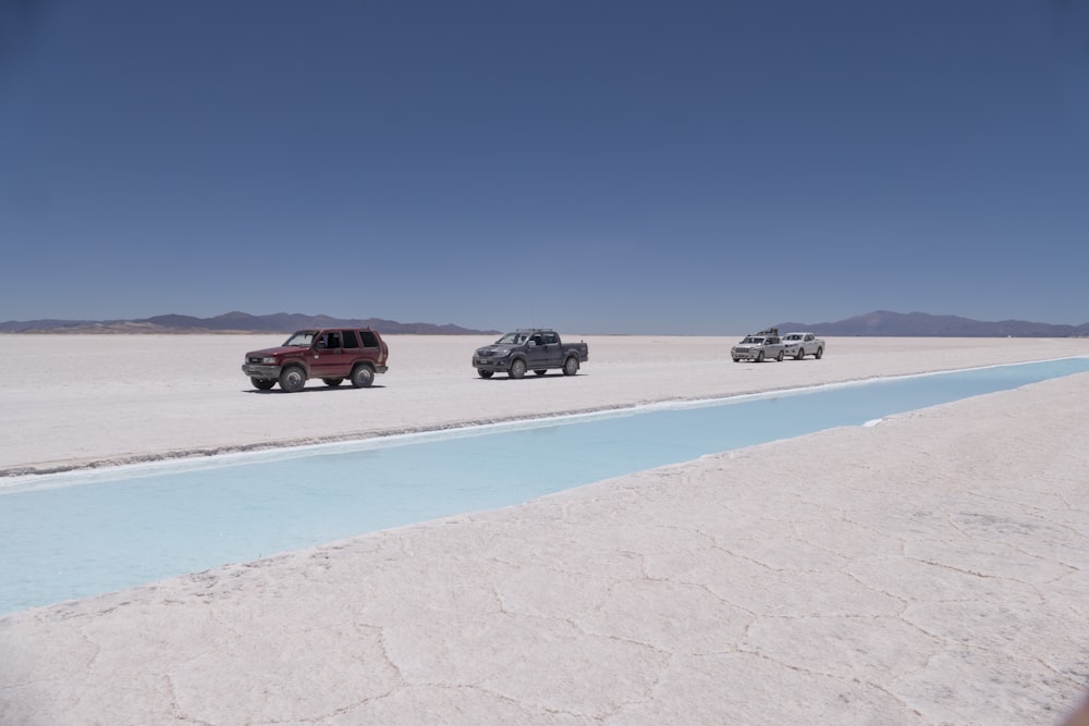 a group of four vehicles driving across a desert