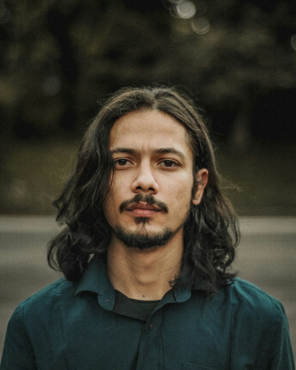 a man with long hair wearing a green shirt