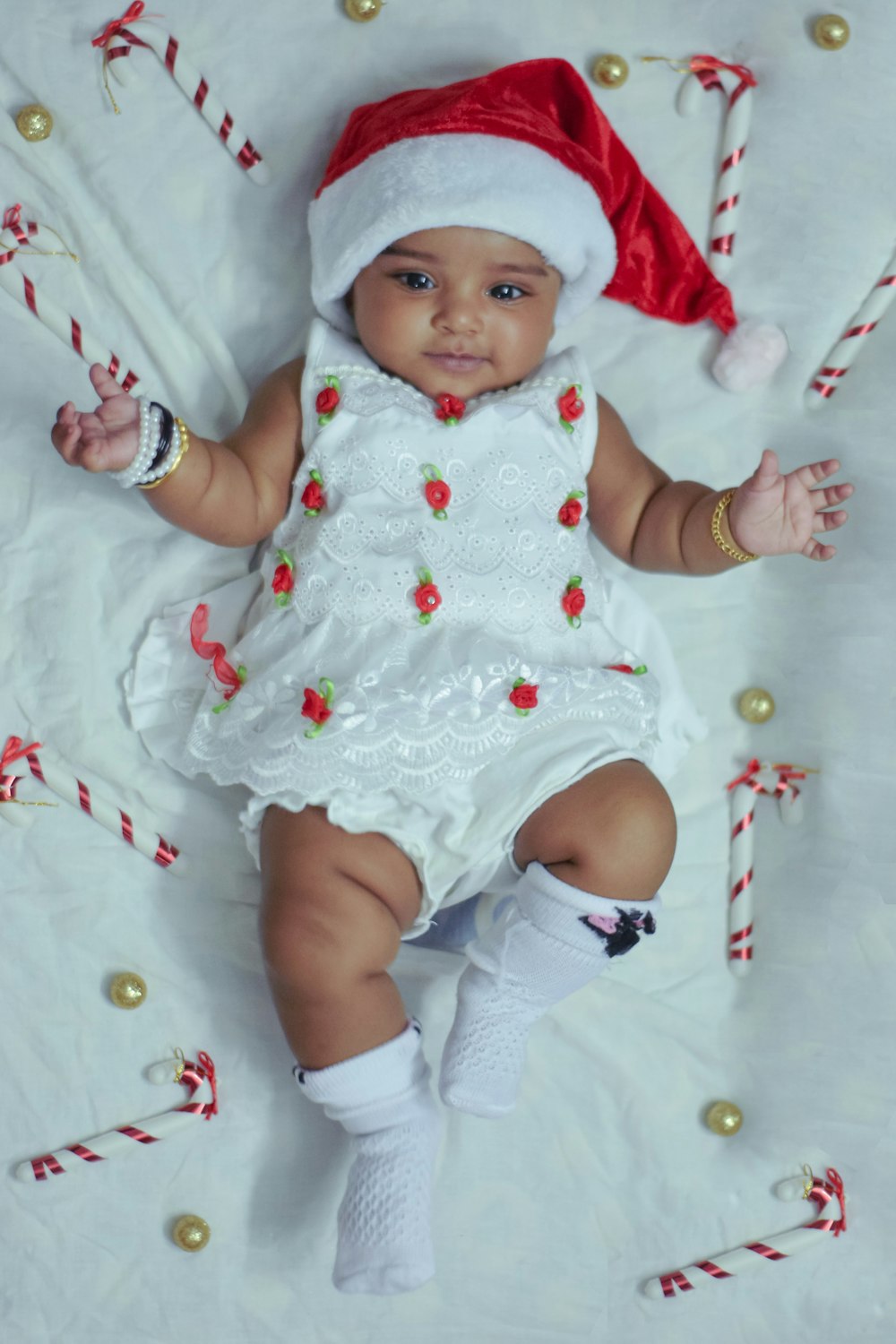 a baby wearing a santa hat and holding candy canes