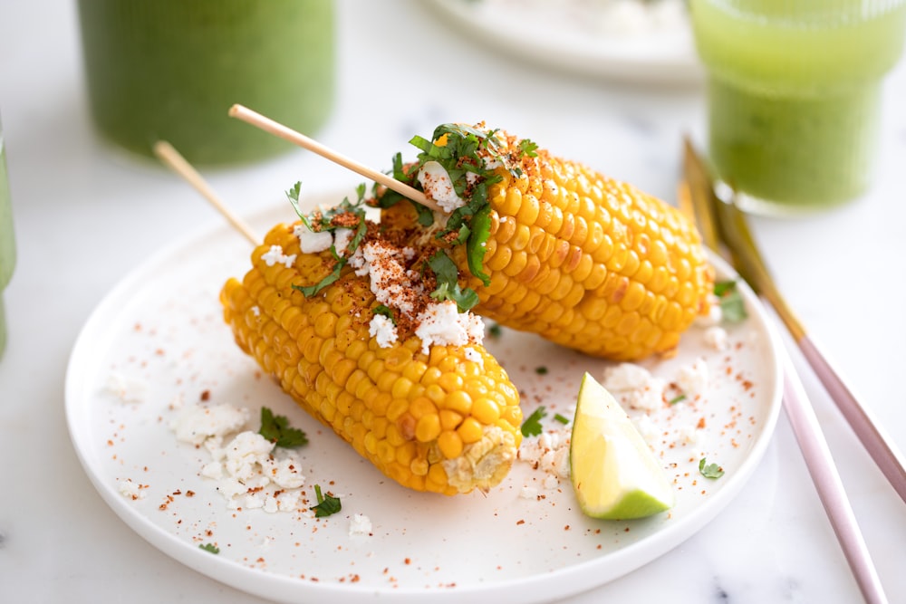two corn on the cob on a white plate