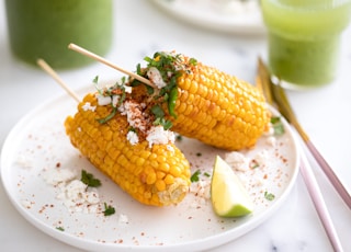 two corn on the cob on a white plate
