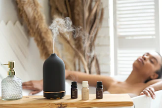 a woman laying in a bathtub next to a bottle of essential oils