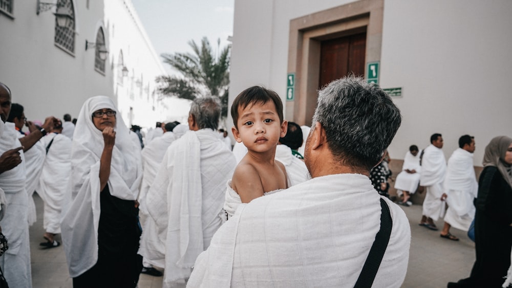 a man holding a small child in front of a crowd of people