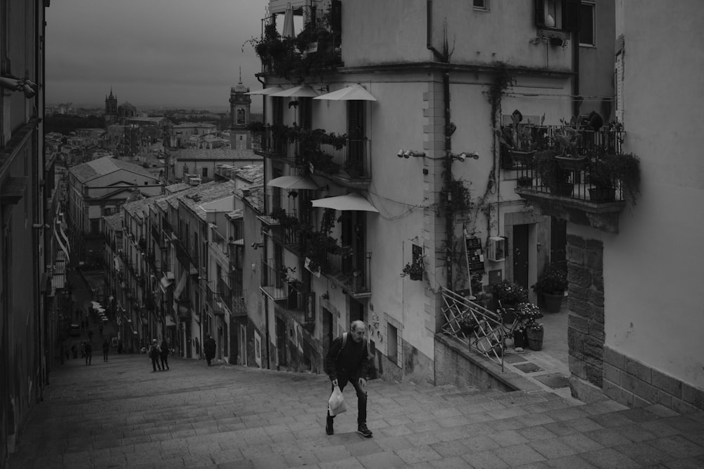 Una foto in bianco e nero di un uomo che cammina lungo una strada