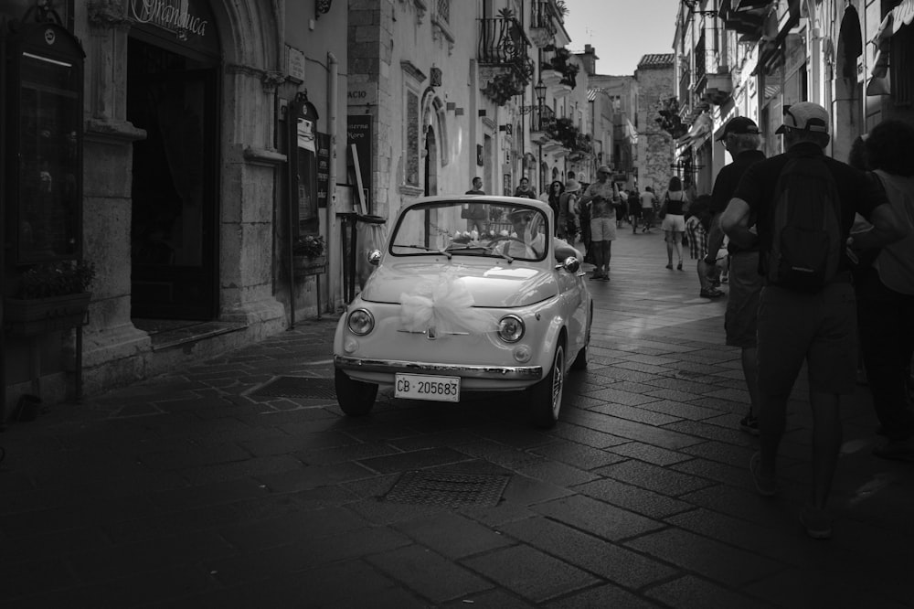 a small car driving down a street next to tall buildings