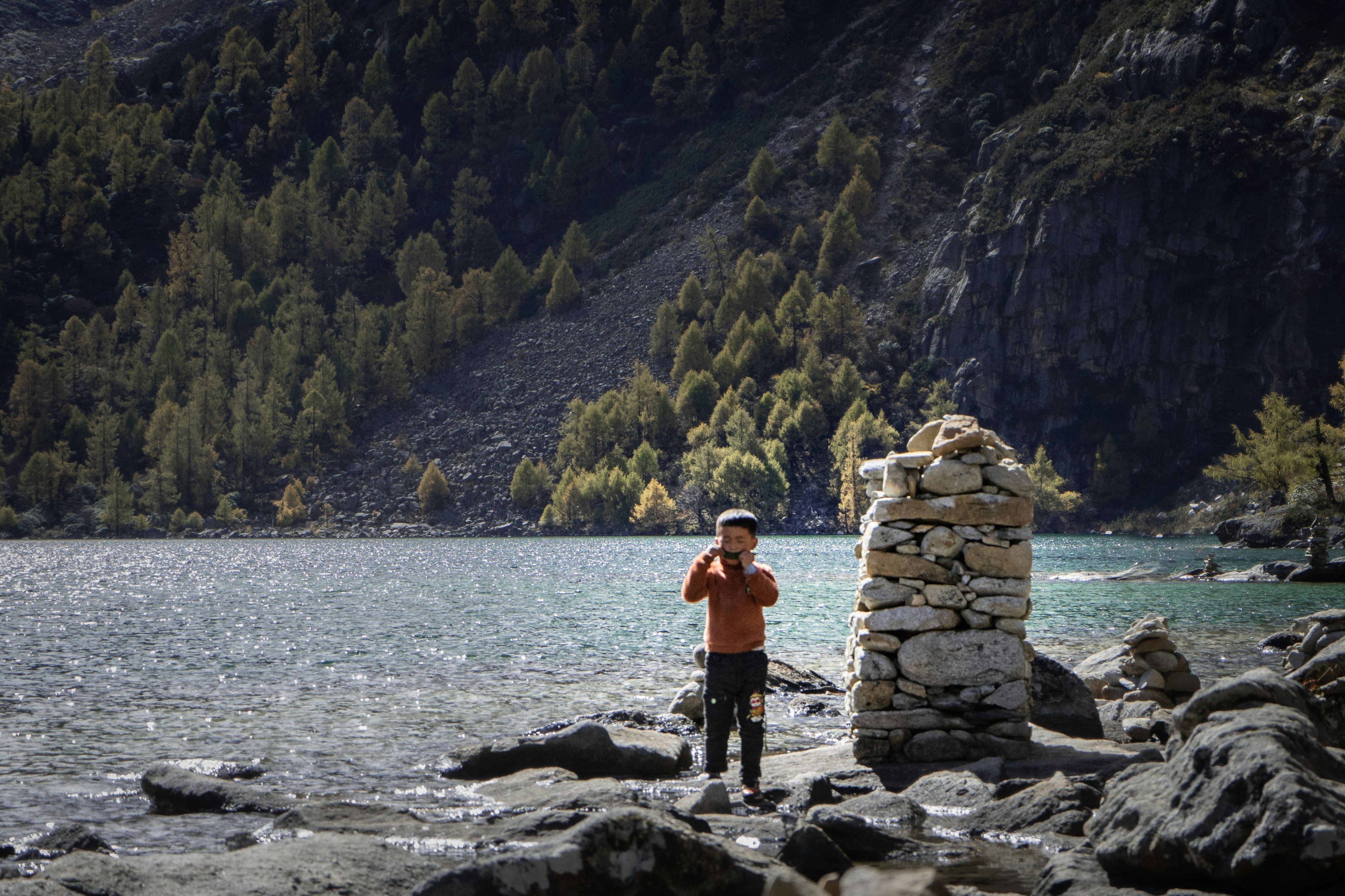 a man standing on a rocky shore next to a body of water