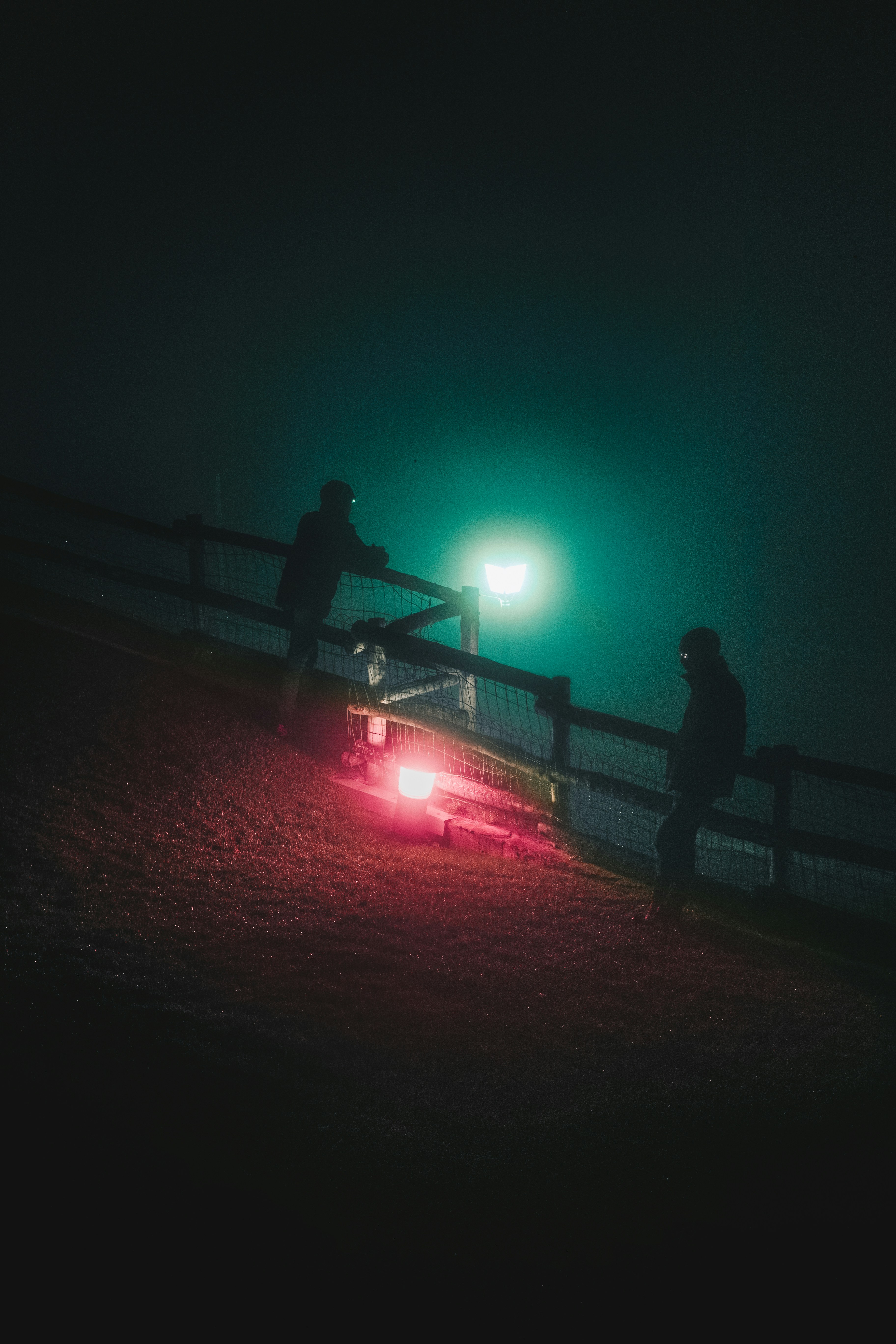 a couple of men standing next to a car at night