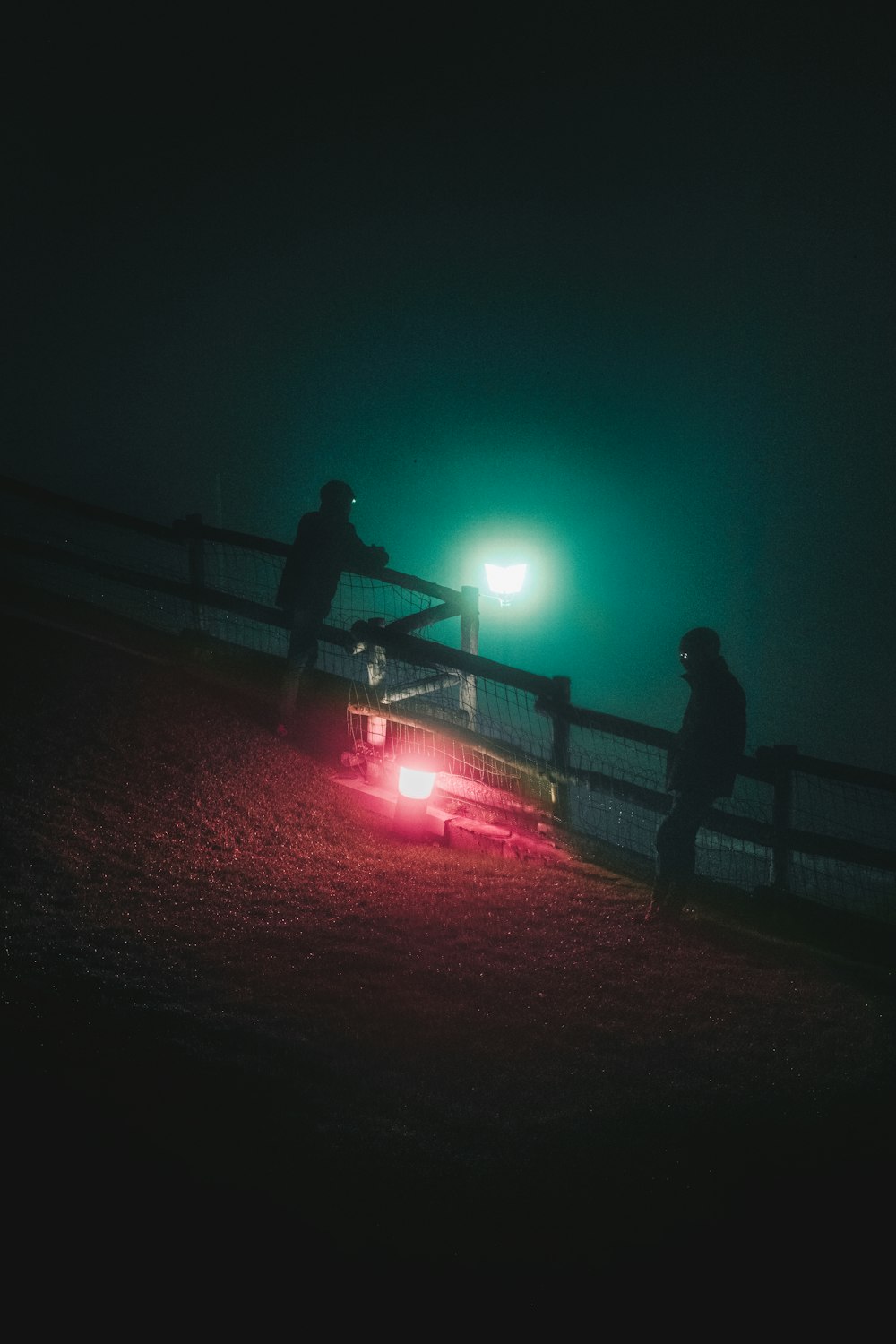 a couple of men standing next to a car at night