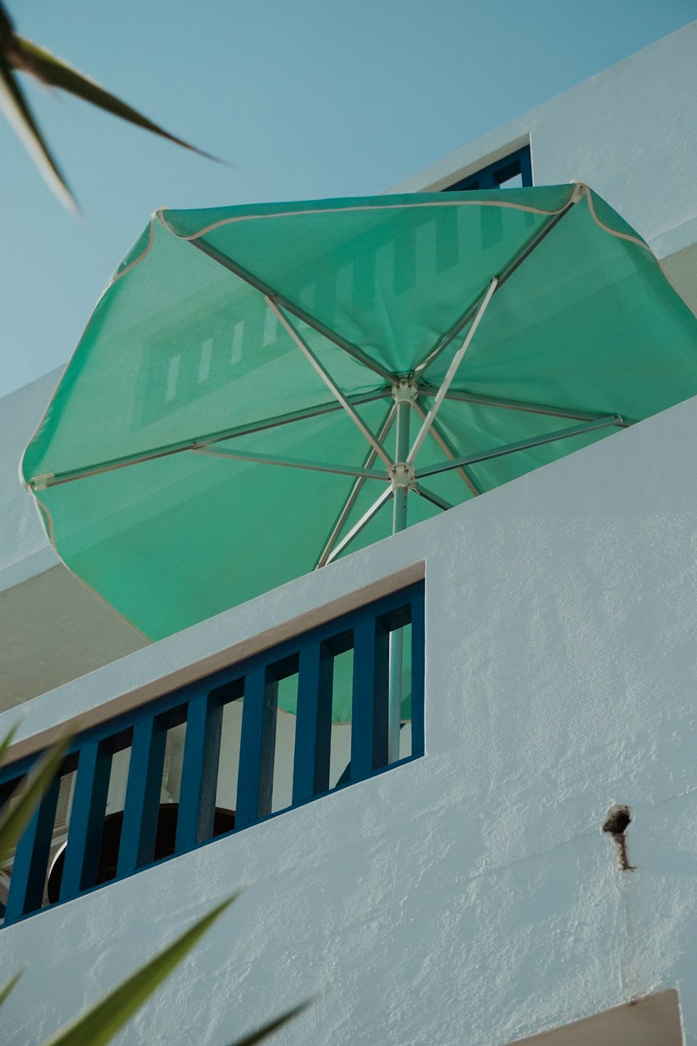 a large green umbrella hanging from the side of a building