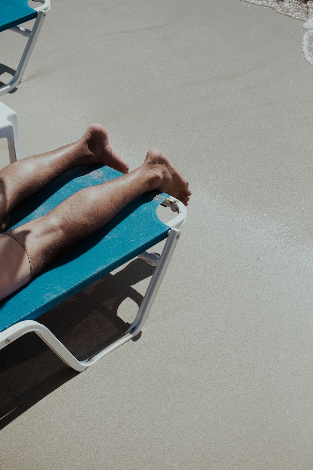 a man laying on a beach chair on the sand