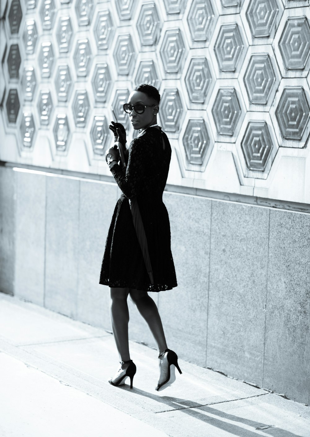 a woman in a black dress and heels walking down the street