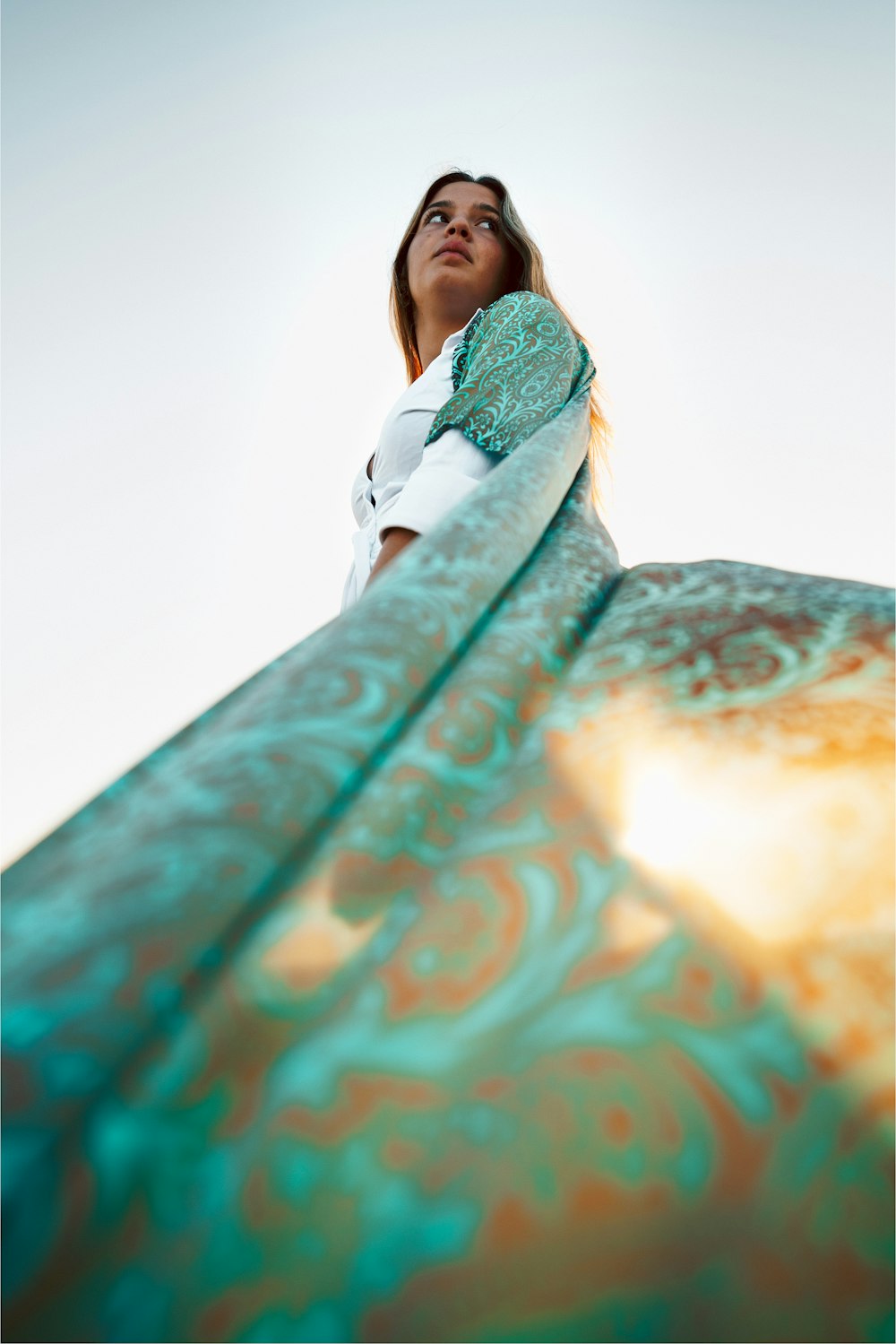 a woman in a white shirt is standing on a surfboard