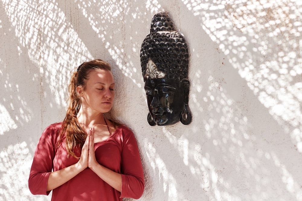 a woman standing in front of a buddha statue