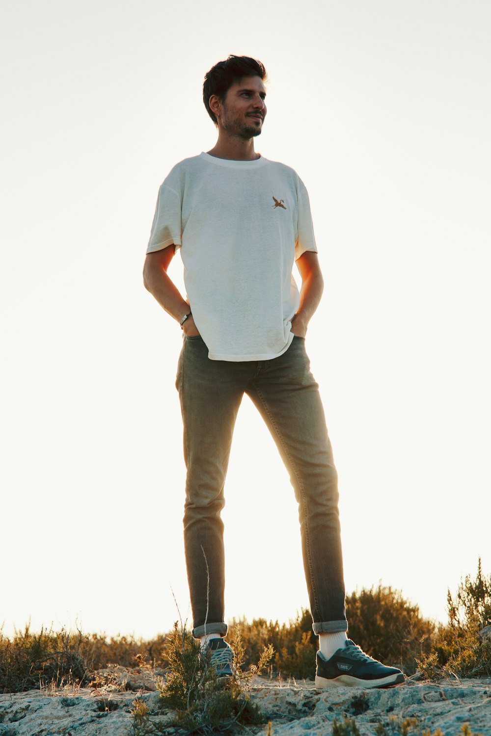 a man standing on a hill with his hands in his pockets