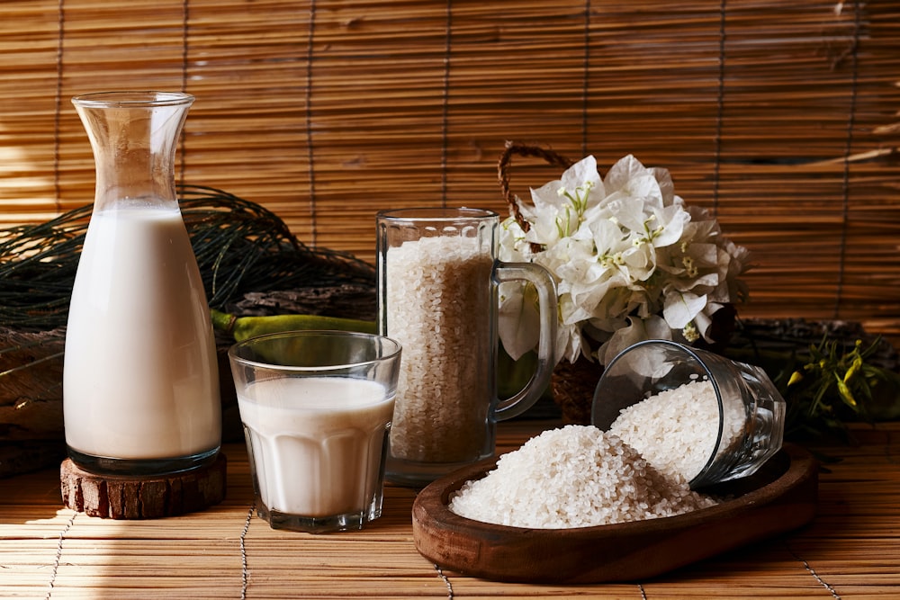 a table topped with a pitcher of milk next to a glass of milk