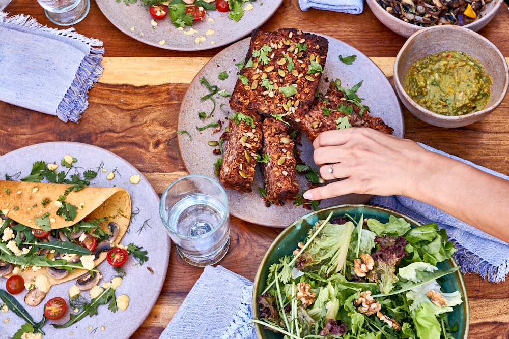 a wooden table topped with plates of food