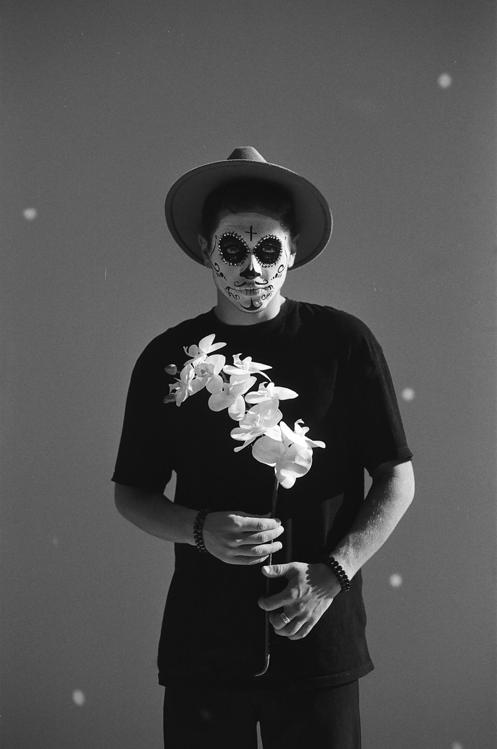 Un hombre con un esqueleto de pintura facial sosteniendo una flor