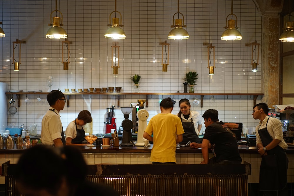 a group of people standing around a kitchen