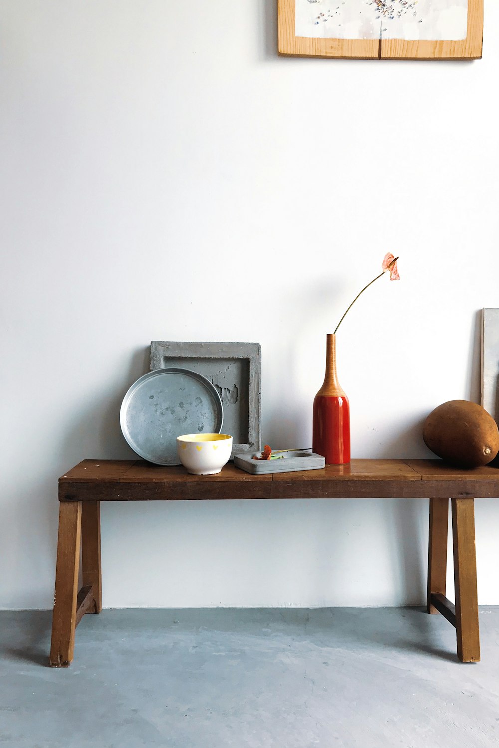 a wooden table topped with a bowl and a vase