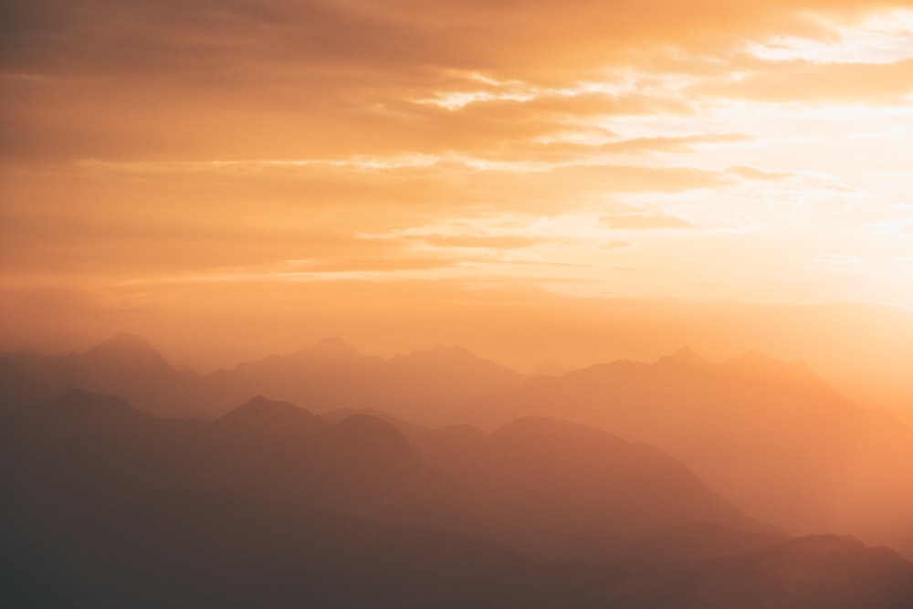 the sun is setting over a mountain range