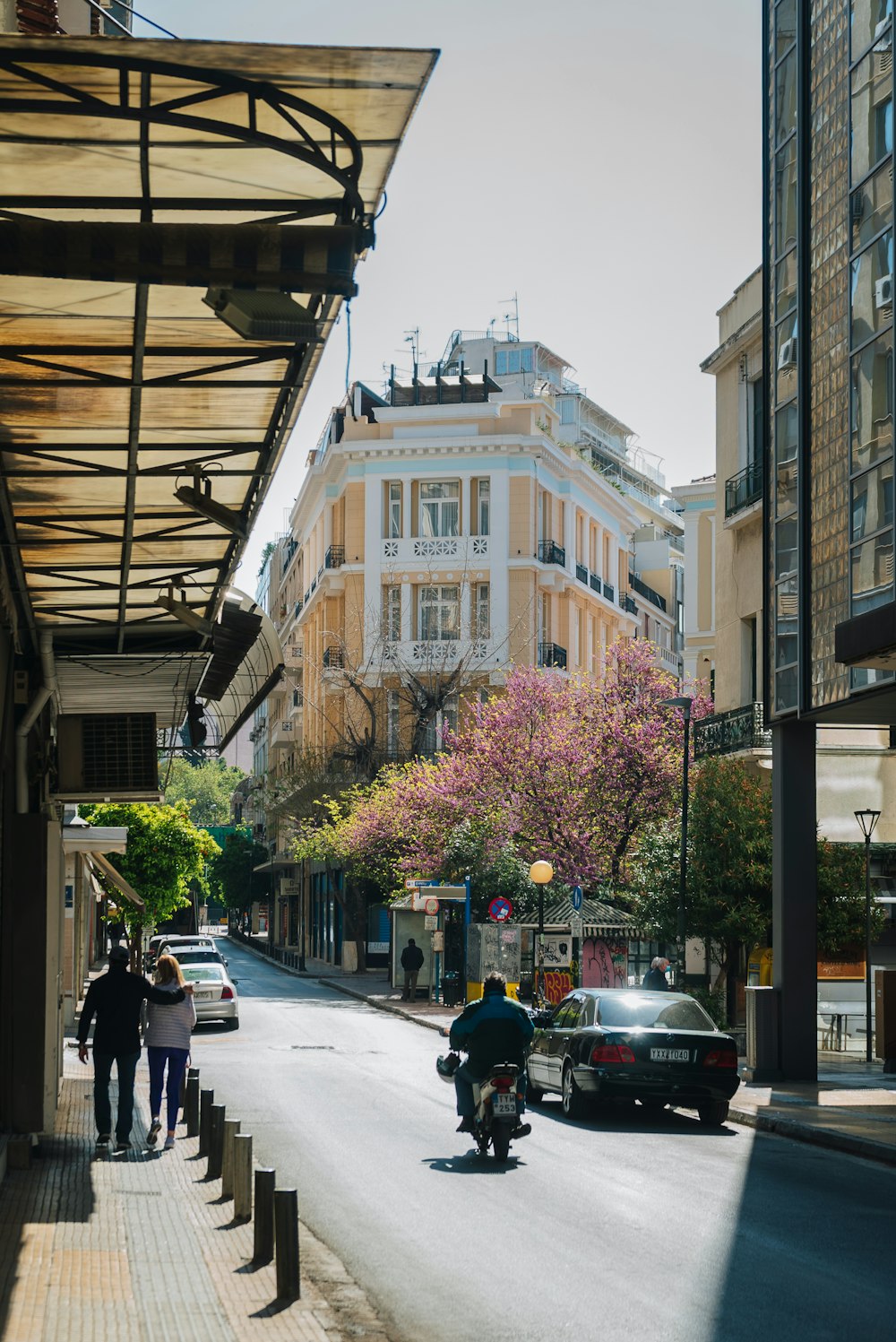 a man riding a motorcycle down a street next to tall buildings