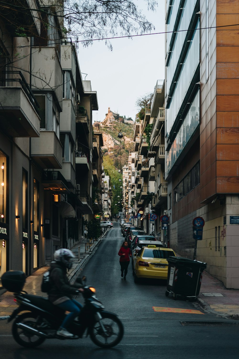 a man riding a motorcycle down a street next to tall buildings