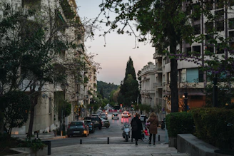 a group of people walking down a street next to tall buildings