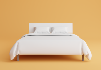 a bed with a white cover and pillows on top of it