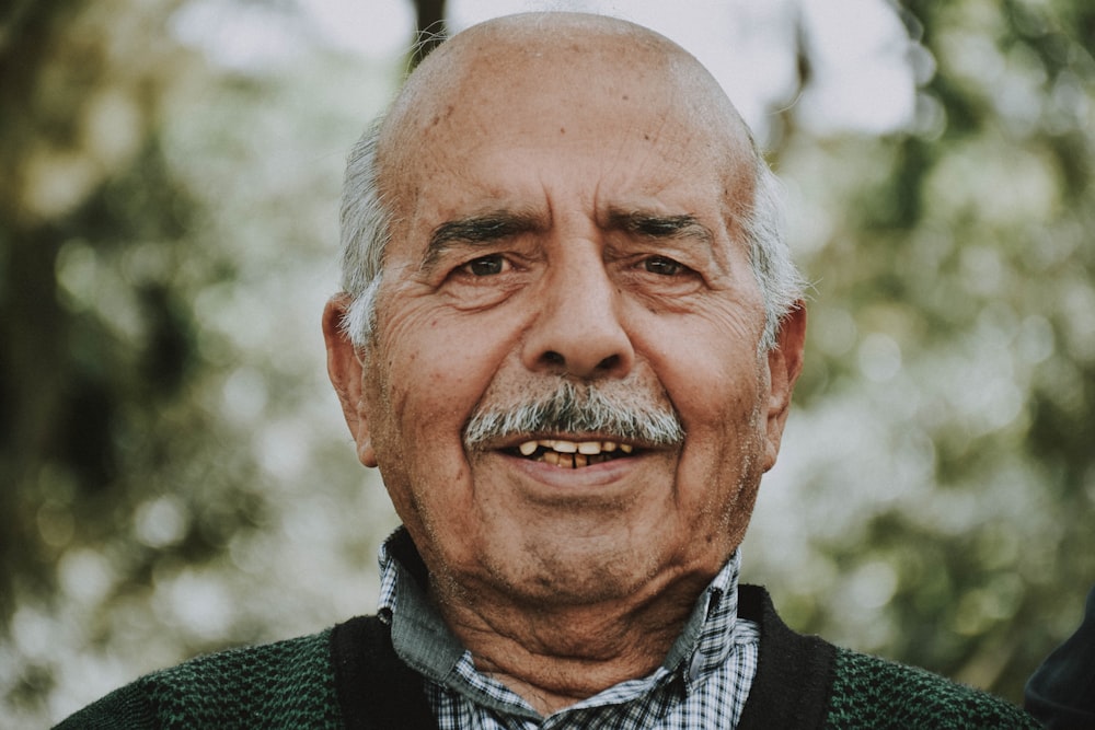 an older man with a mustache and a green sweater