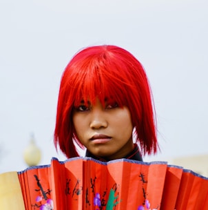 a woman with red hair holding a red fan