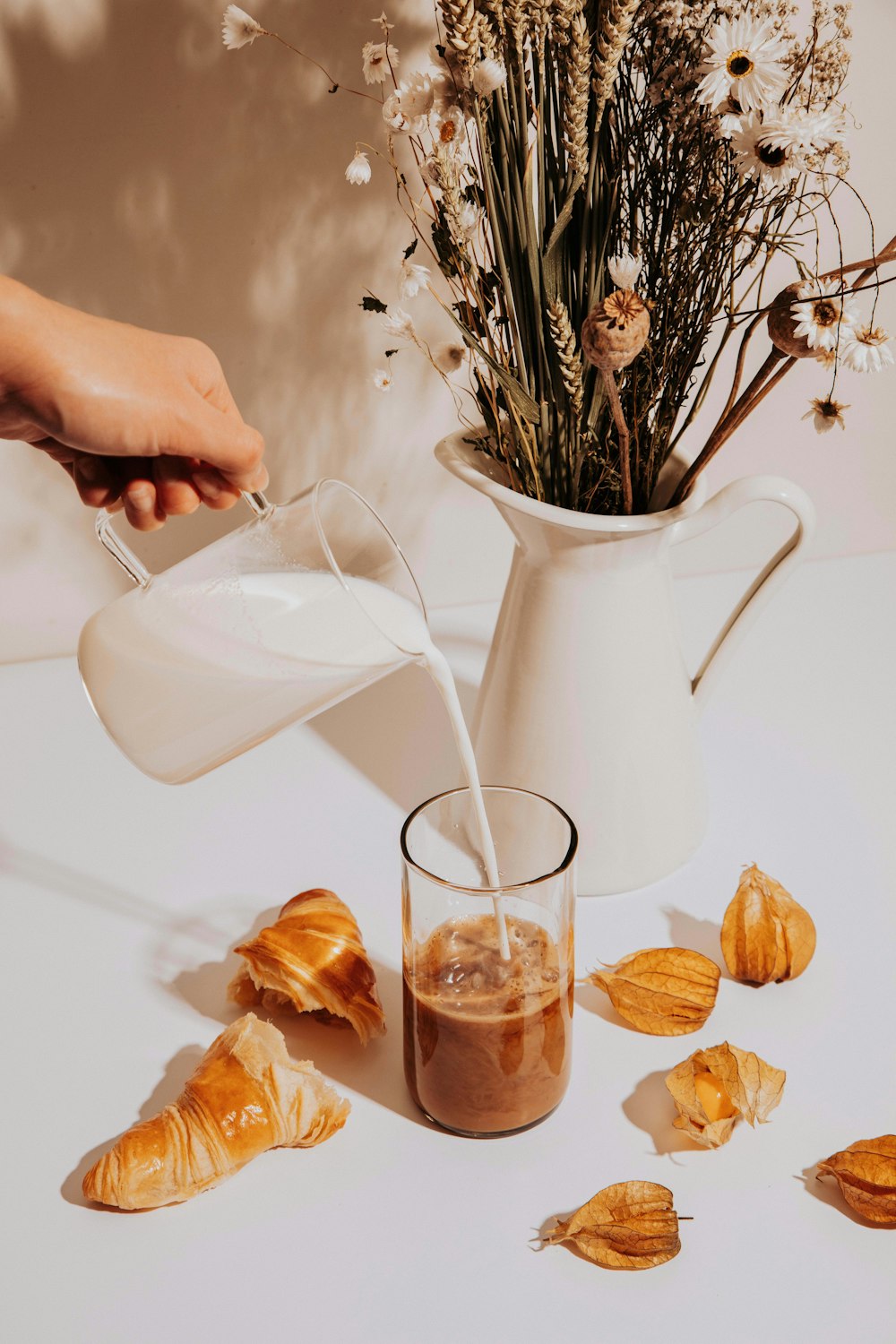 a pitcher of milk being poured into a glass