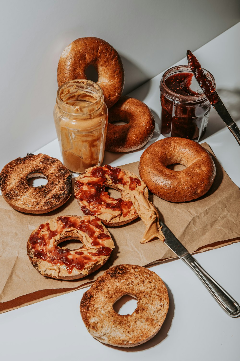 a table topped with donuts and pizzas next to a jar of peanut butter