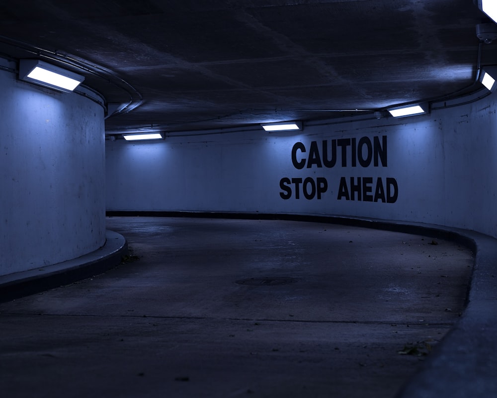 a dark parking garage with a caution sign on the wall