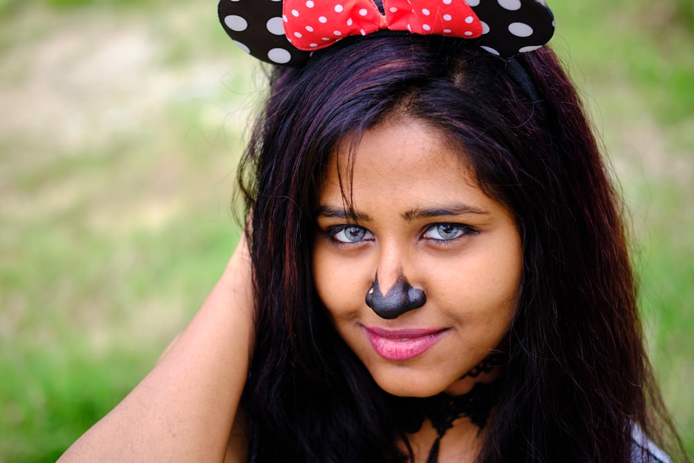 a girl with a black nose and a red minnie mouse ears