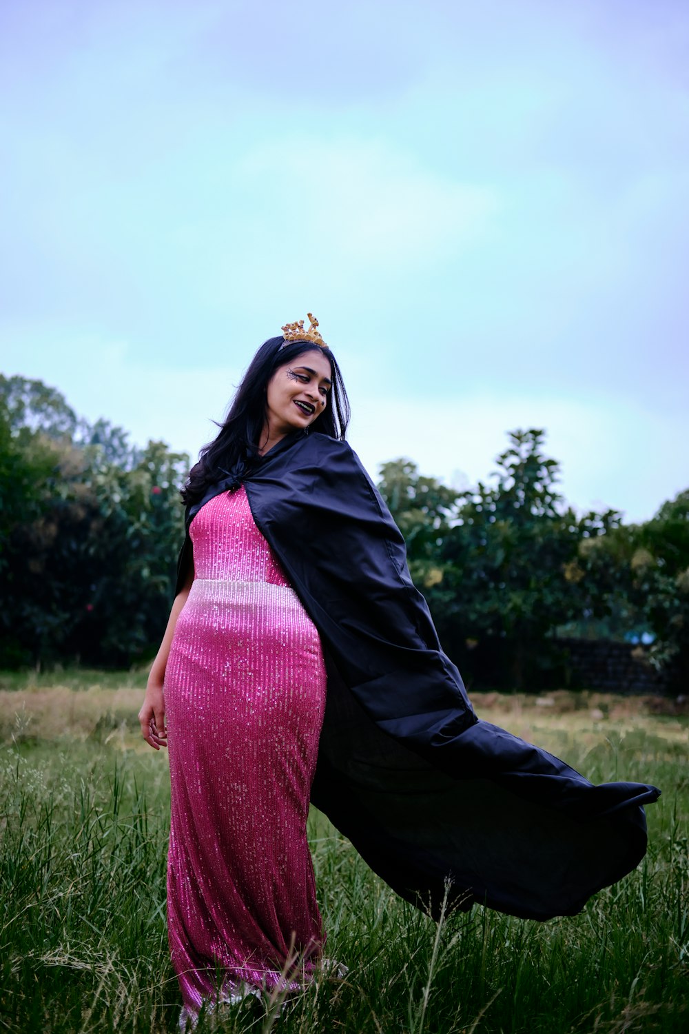 a woman in a pink dress and a black cape