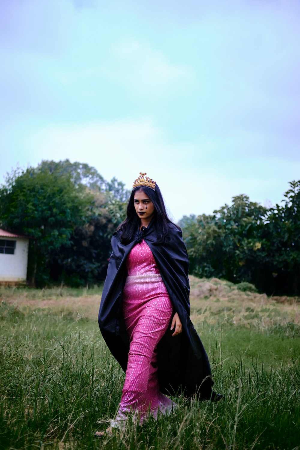 a woman in a pink dress and a black cape