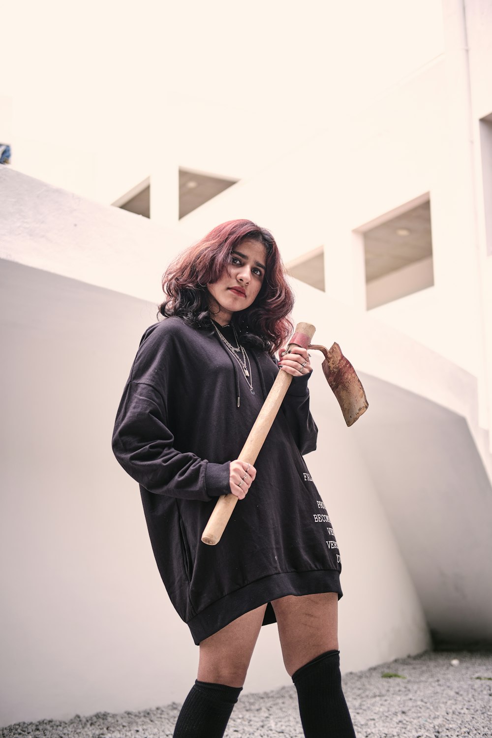 a woman in a black hoodie holding a baseball bat