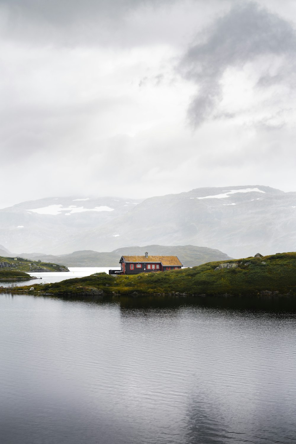 a house sitting on top of a hill next to a body of water