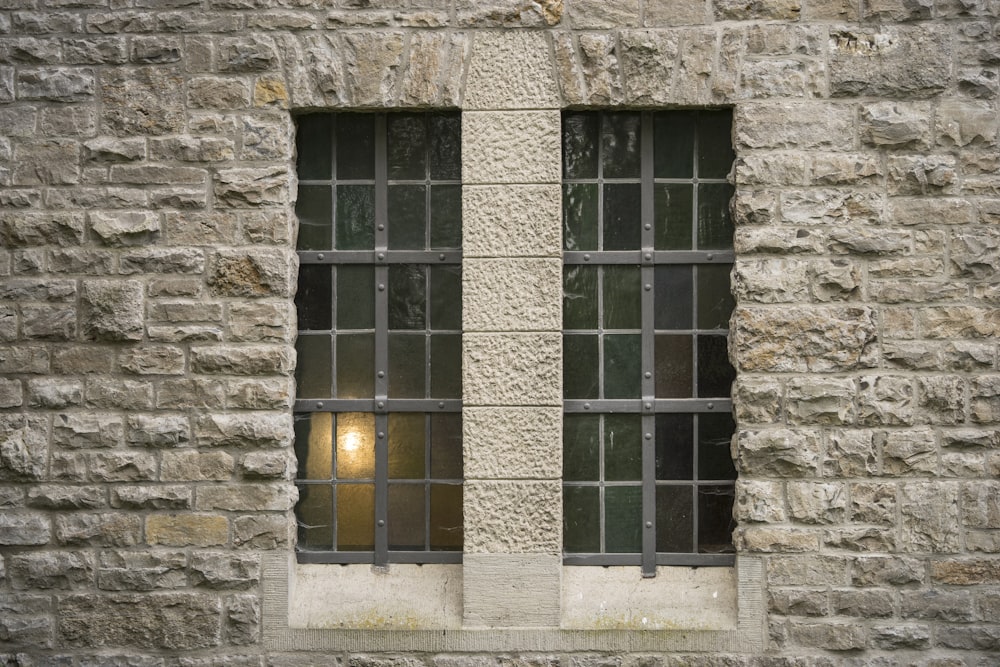 a brick wall with two windows and bars