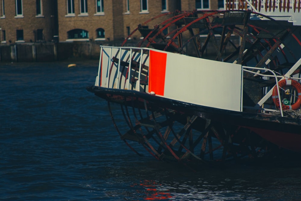 a red and white boat floating on top of a body of water