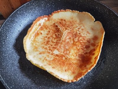 A close-up of golden Dutch baby pancakes cooking on a rustic griddle