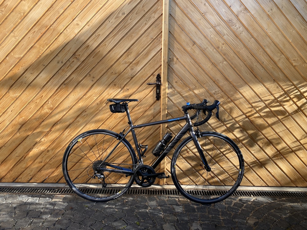 a bicycle parked in front of a wooden wall