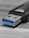 A close-up view of a USB flash drive on a textured surface, highlighting the metal connector with a blue plastic insert characteristic of USB 3.0. The drive's black housing is partially visible.