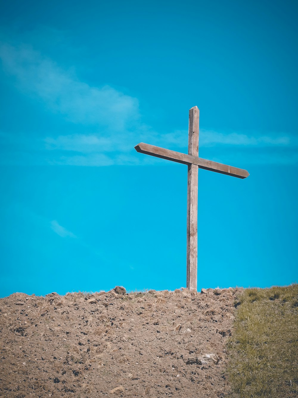 uma cruz de madeira sentada no topo de uma colina