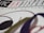 A close-up view of a graphic design featuring the text 'ON DISPLAY' highlighted in red on a white background. The letters are bold and part of a limited edition print design. Curved lines and shapes in black, green, and red are artistically arranged around the text.