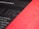 A close-up view of a printed page with a blurred mix of black and red sections. The text 'for the design' is partially visible and the overall appearance is abstract and artistic.