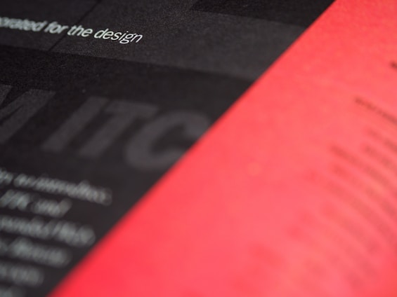 A close-up view of a printed page with a blurred mix of black and red sections. The text 'for the design' is partially visible and the overall appearance is abstract and artistic.